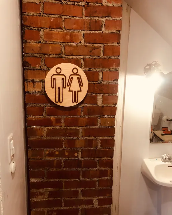 The restroom sign mounted on a brick wall